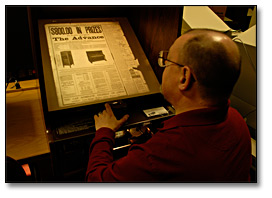 Photographie : Un chercheur utilise un lecteur de microfilms dans la salle de lecture principale