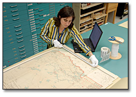 Photo: An archivist measuring a map