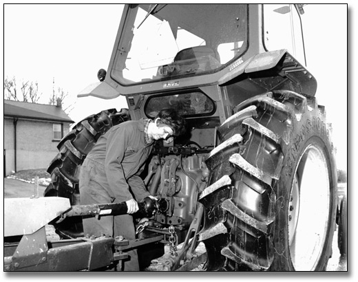 Photo: Farm wife working on a tractor, March 28, 1984
