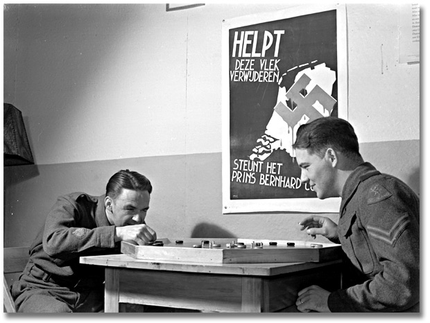 Photographie : Dutch troops playing crokinole; Dutch war poster in background, avril 1941