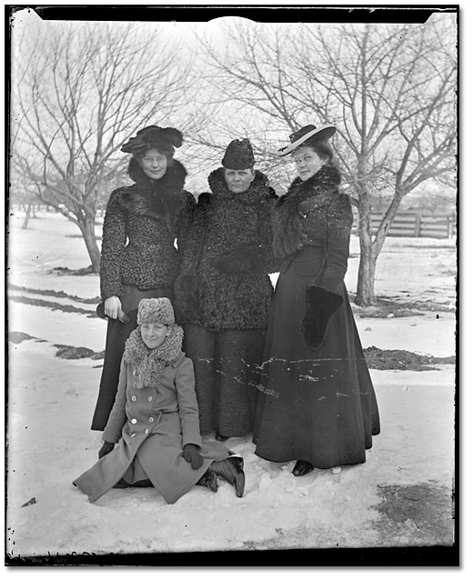 Photo: Three women and a child posed outside during the winter, [between 1898 and 1920]