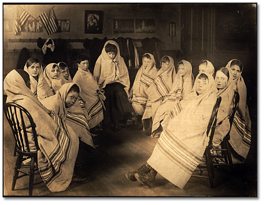 Photographie : Enfants enveloppés dans des couvertures attendant la visite de l’infirmière de l’école, [vers 1905]