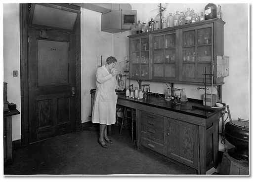 Photo: A woman examining milk at a Board of Health laboratory, [ca. 1928]