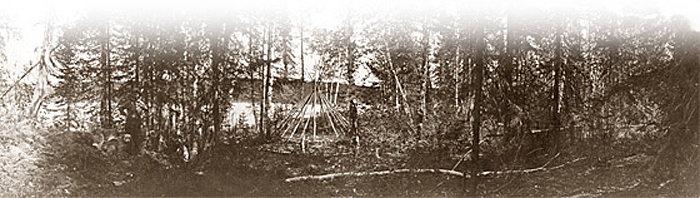 Photographie : Un jeune homme et des cheins près d'un tipi en construction [vers 1915] - bannière