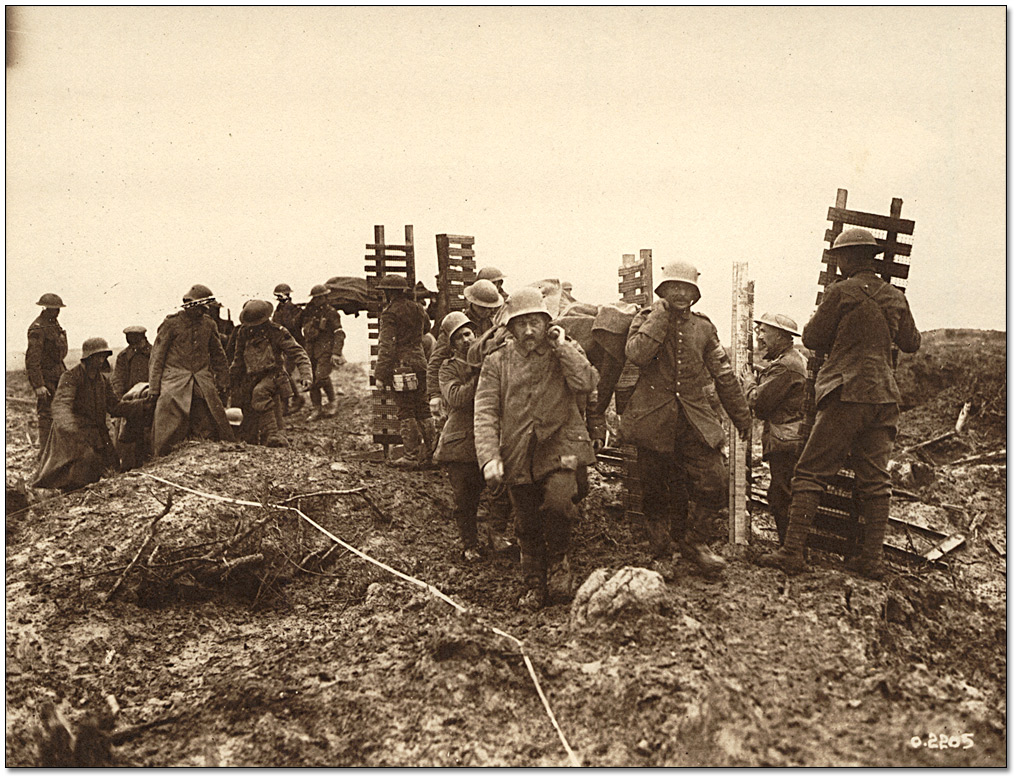 Photographie : Des pionniers canadiens amenant du matériel de tranchées à Passchendaele retournent du travail, et croisent des prisonniers allemands transportant des blesses, 1917