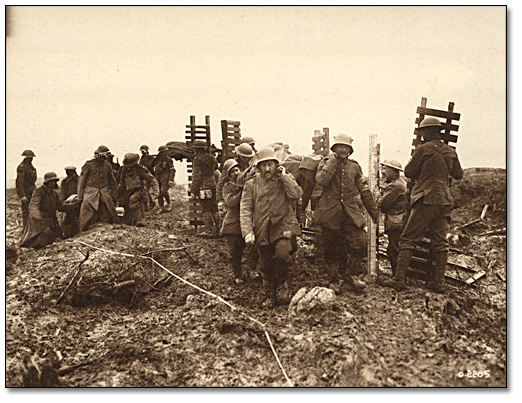 Photographie : Des pionniers canadiens amenant du matériel de tranchées à Passchendaele retournent du travail, et croisent des prisonniers allemands transportant des blesses