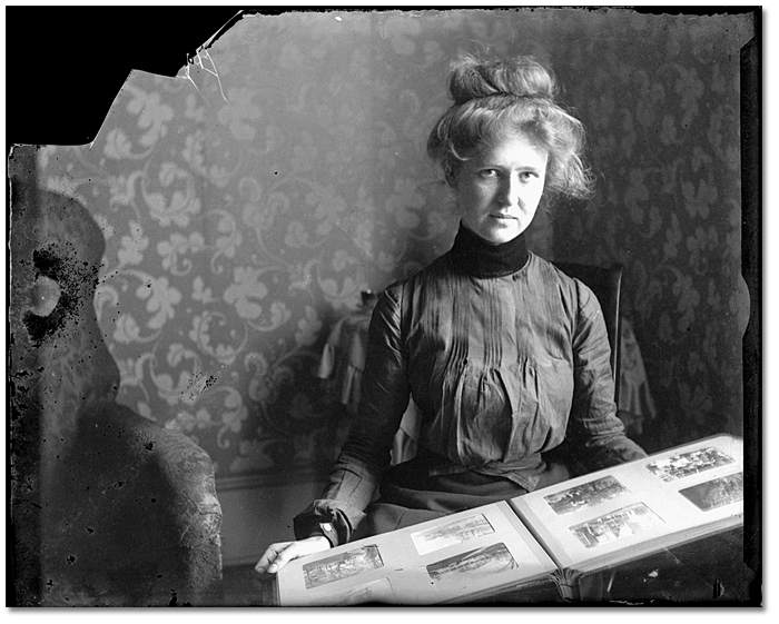 Lola M tenant un album de photographies, [entre 1898 et 1910] 
