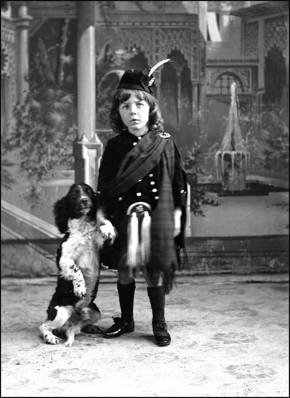 Un garçon en costume écossais avec un chien, [vers 1900]