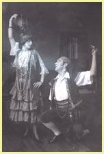 Actors K. McCarthy (standing at left) and Ernest Morgan (on one knee at right), both posed with one arm raised.