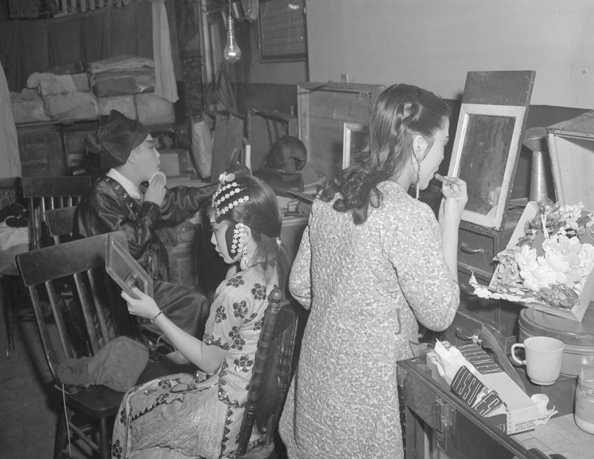 Three Chinese theatre actors applying makeup backstage before a performance in Toronto in 1946.