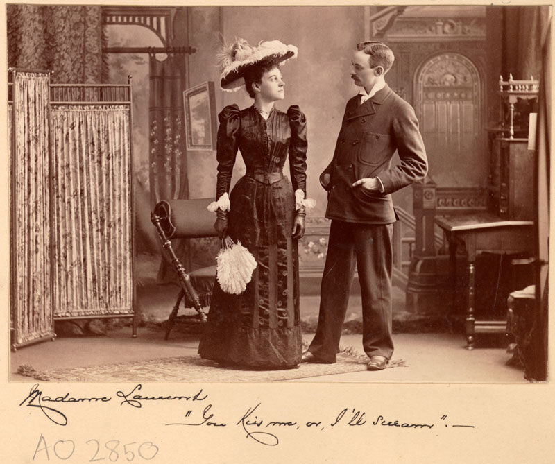 Two white actors. A well-dressed man and woman look intently at one another. The woman’s lines are below.