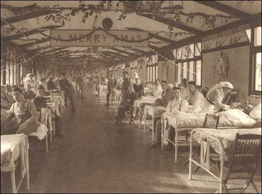 Interior of a military hospital showing patients, visitors and nurses during Christmas time, ca. 1918.