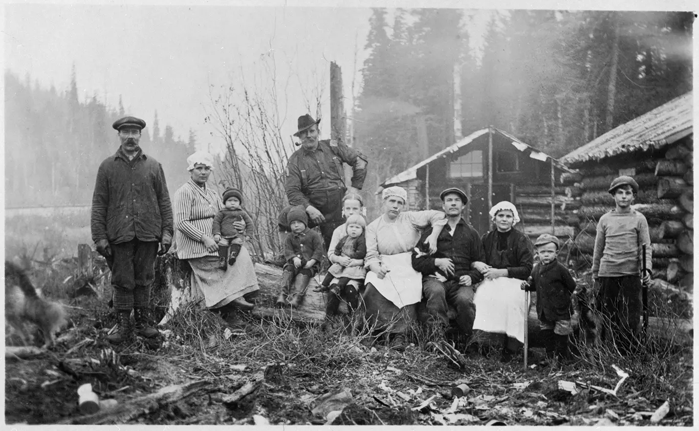 A black and white photo of a multi-generation family standing in a forest clearing.
