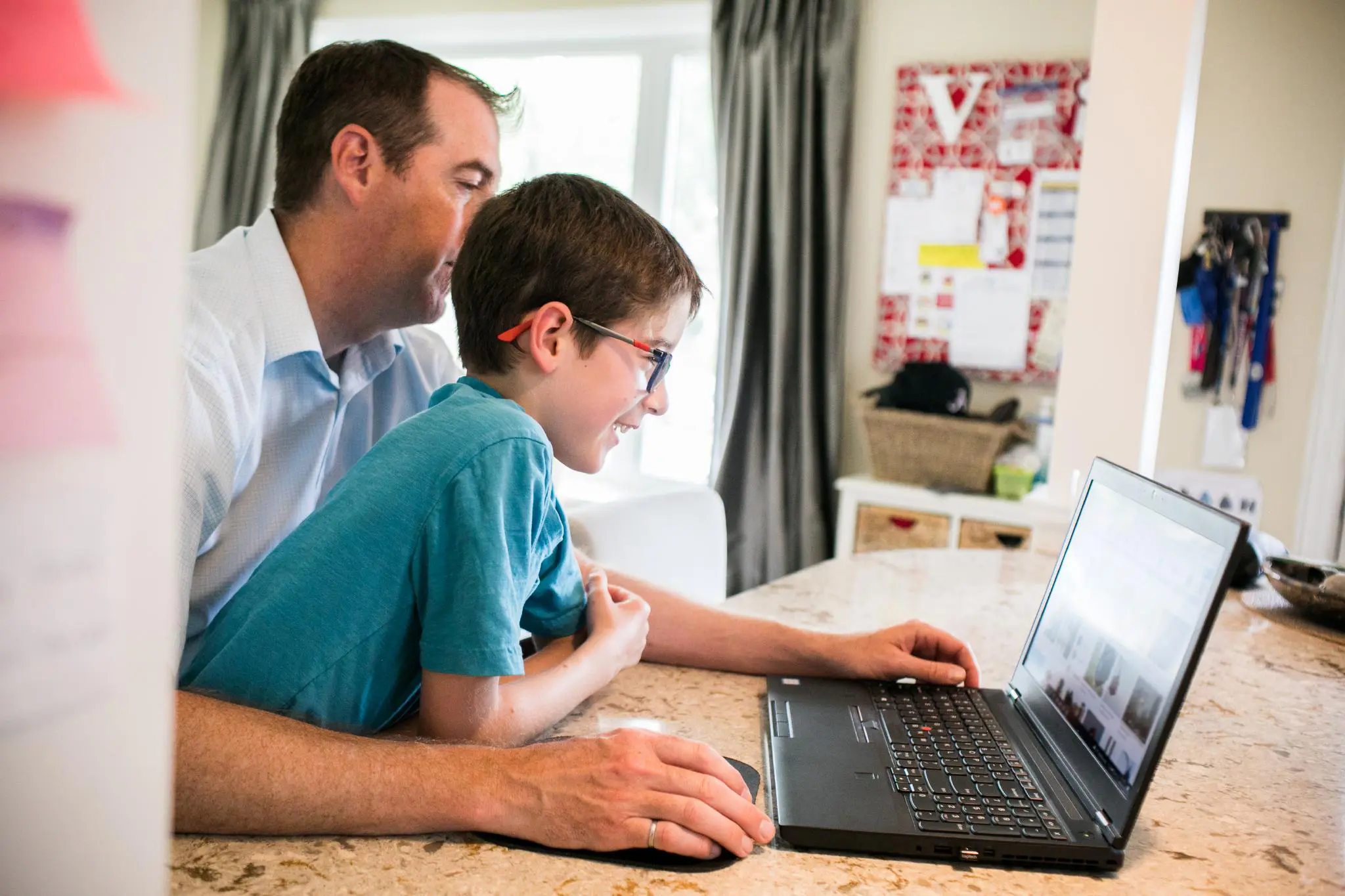 Father and son looking closely at a laptop screen