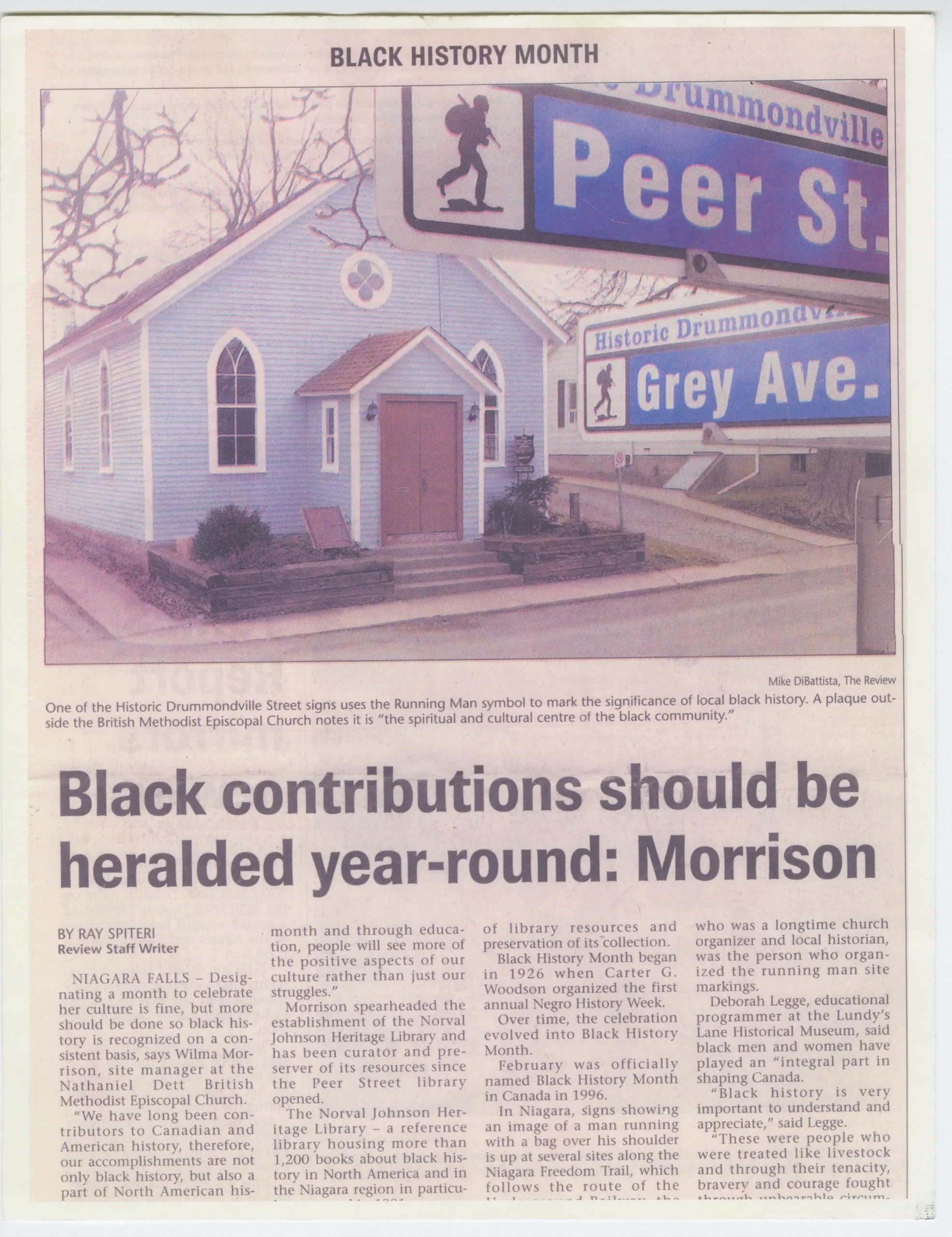 Photo en couleur tirée d’un article de journal, montrant une petite église en bois et deux plaques de rue indiquant « rue Peer » et « avenue Grey ».