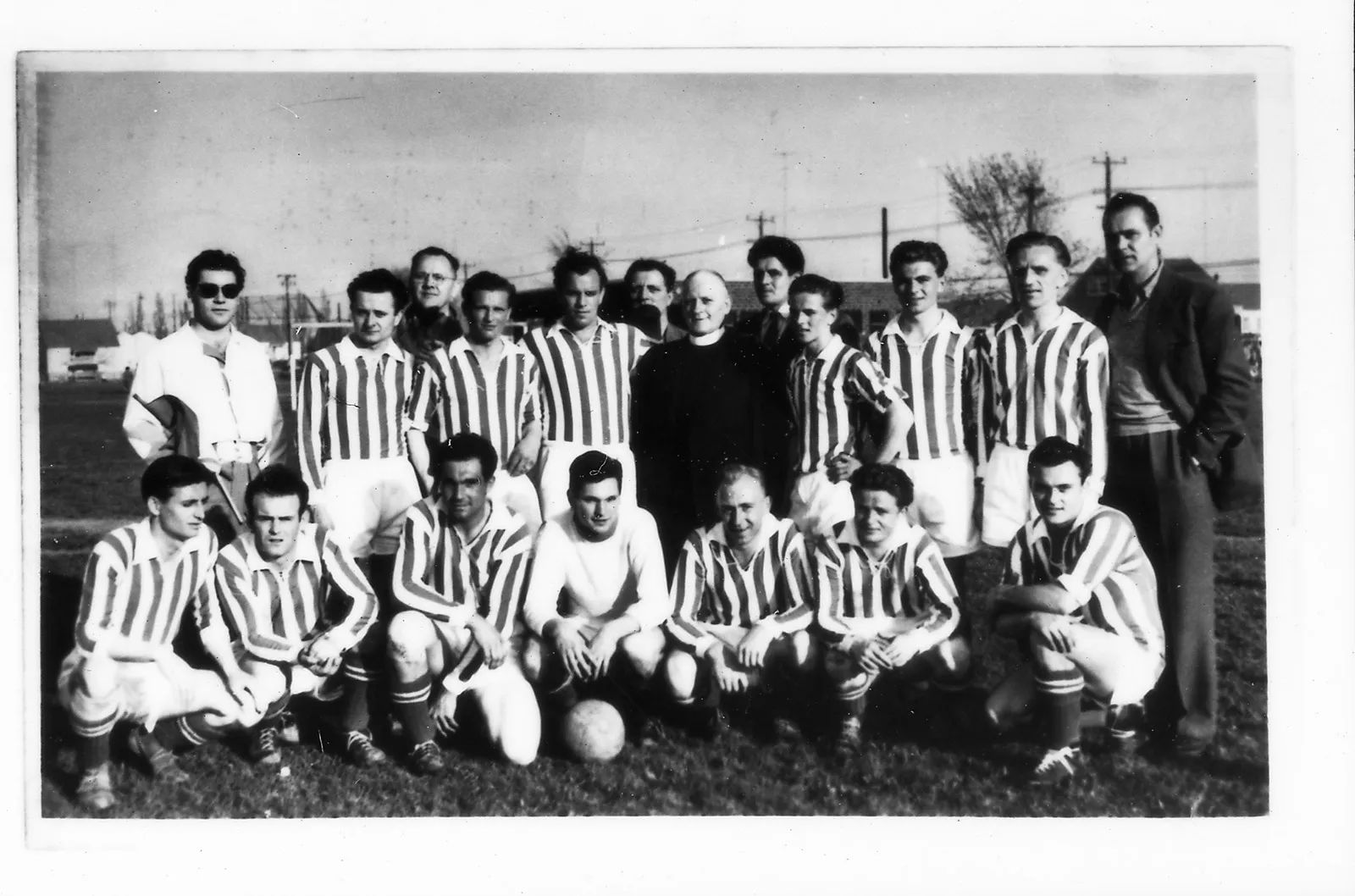 Black-and-white team photo of a soccer team outdoors, with players arranged in two rows wearing striped jerseys.