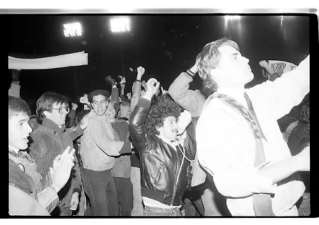Black-and-white photo of unruly fans in a soccer stadium following the loss of the Blizzard soccer team. Fans raise their hands up in the air in anger as they rush toward the field.