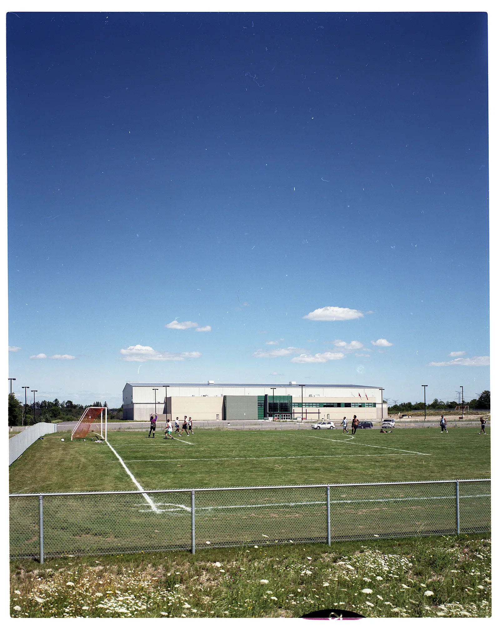 Colour photo of the Ontario Soccer Centre, seen from across a large soccer field where a scrimmage is taking place.