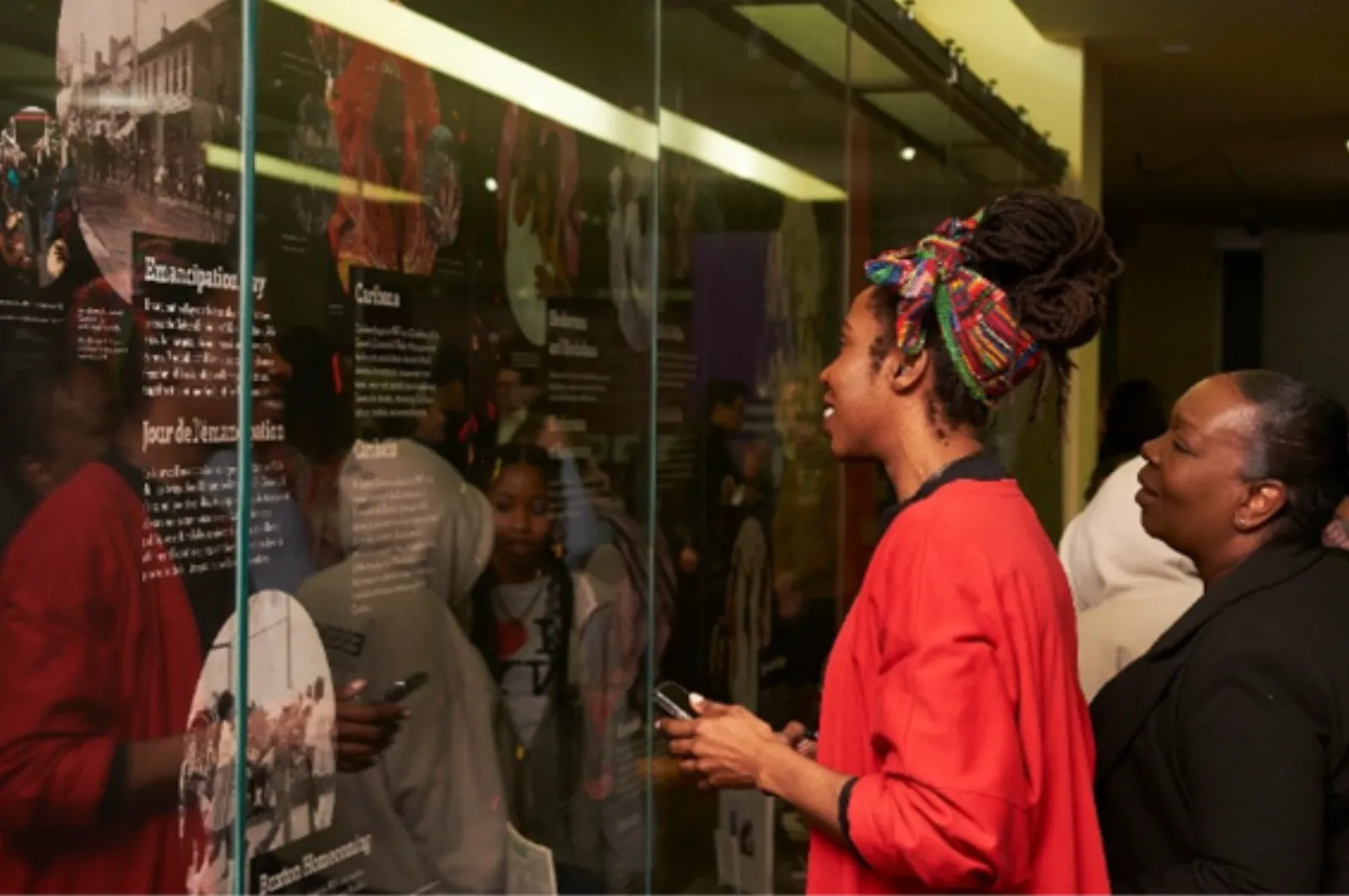Deux femmes examinent des documents d’archives présentés derrière une vitrine d’exposition.