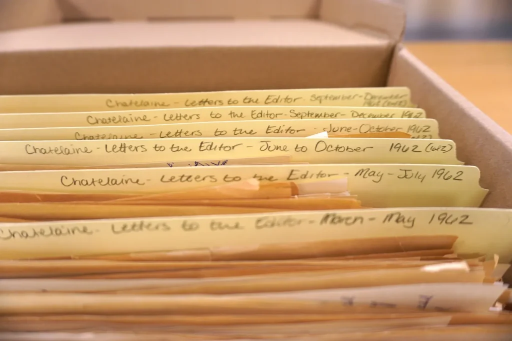 Close-up view of archival file folders arranged in a records box. Handwritten labels on the folder tabs read “Chatelaine - Letters to the Editor” and identify date ranges by month in 1962. The folders contain correspondence and are organized chronologically within the archival collection.