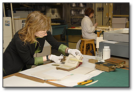 Photo: A conservator remounting photographs