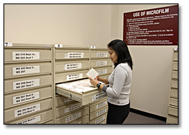 Photo: Researcher retrieving microfilm from the self-serve microfilm draw in the Reading Room