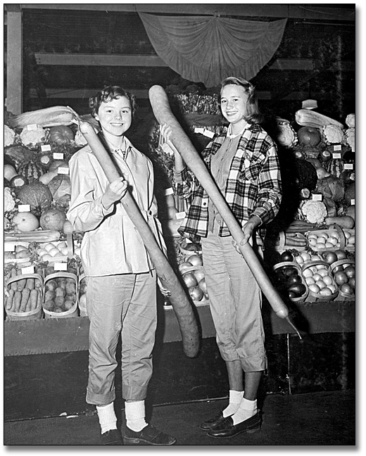 Photographie : Deux femmes de Port Hope avec des courges italiennes à la Foire agricole royale d’hiver, Toronto, 1955