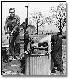 Photographie : Two men at a water pump at a farm service camp, [vers 1950]