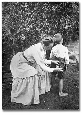 Photographie : Mère cousant les pantalons d’un jeune garçon, 1904