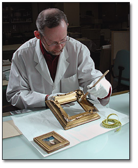 Photo of conservator cleaning frame