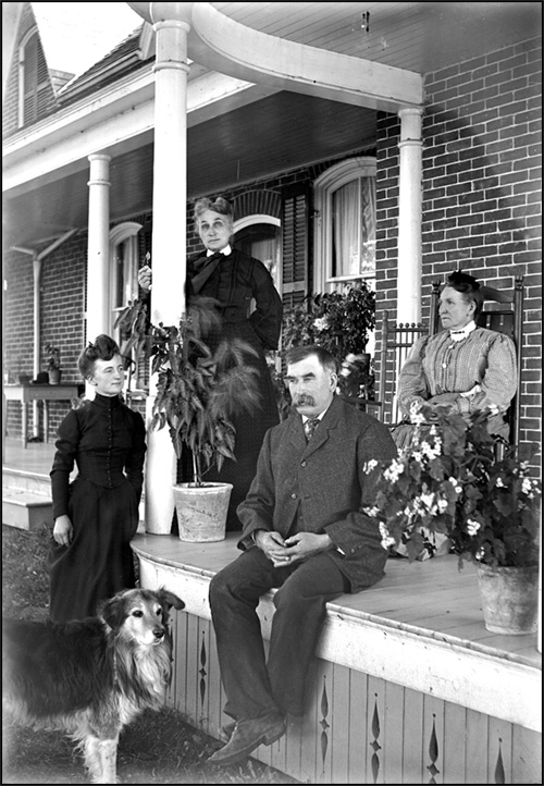 Man, three women, and a dog on a veranda, [between 1898 and 1920]