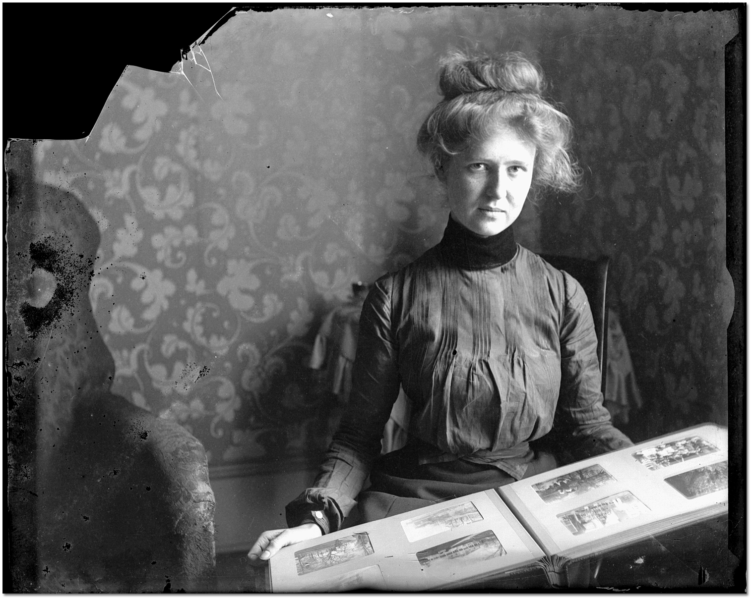 Lola M tenant un album de photographies, [entre 1898 et 1910]