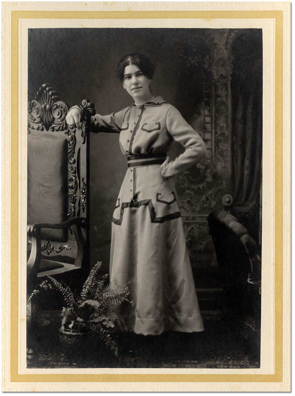 Portrait of an unidentified young woman posing beside a chair, [between 1900 and 1920]