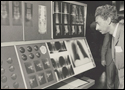 Photo of a man looking at a microfilm reel with a magnifying glass